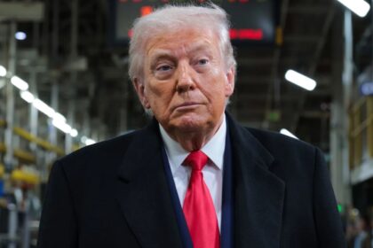 Donald Trump wearing an elegant suit while walking through a manufacturing facility
