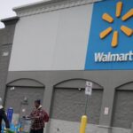 A panoramic photo of one of Walmart’s stores with several people walking out of it
