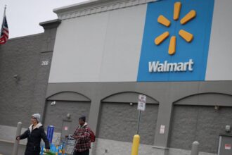 A panoramic photo of one of Walmart’s stores with several people walking out of it