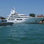 A luxurious white yacht docked at a small harbor in the city of Venice, Italy