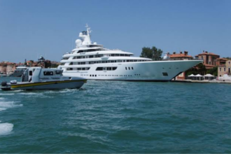 A luxurious white yacht docked at a small harbor in the city of Venice, Italy