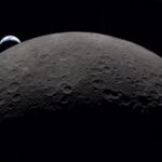 A view from the Moon showing planet Earth rising behind the lunar surface