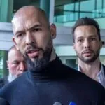 The Tate brothers walking while surrounded by numerous members of the media seeking information from them