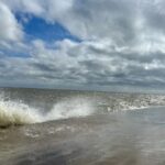 A beach being violently battered by waves crashing against a seawall, creating a tense and unsettling atmosphere