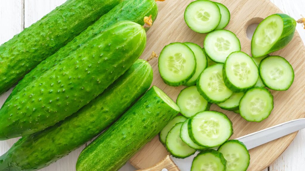 Cucumbers surprise with their incredible health benefits Several cucumbers stacked on a table, with one cucumber sliced into pieces beside them and a knife placed nearby