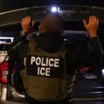 Death of Colombian man during ICE operation sparks calls for answers in the United States An ICE officer in uniform inspecting the trunk of a parked car