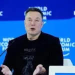 Elon delivering a speech while sitting comfortably in an armchair