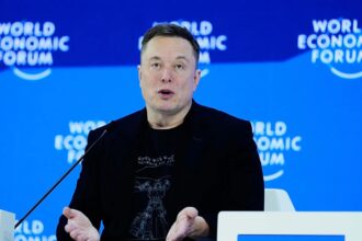 Elon delivering a speech while sitting comfortably in an armchair