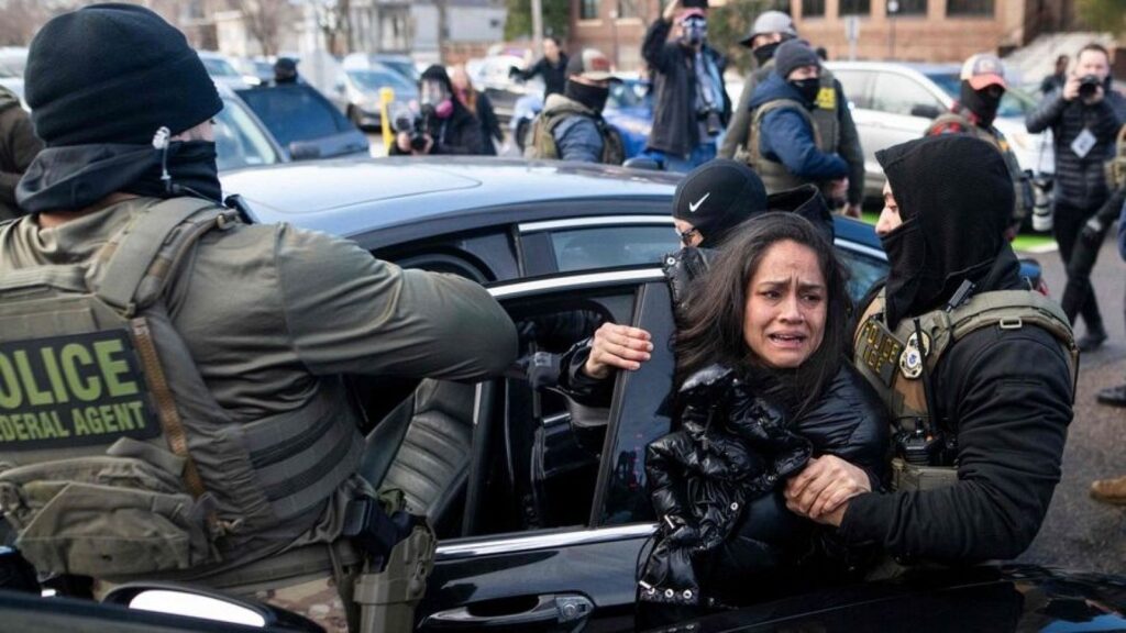 Several ICE agents attempting to place a woman into a vehicle as she cries and struggles to avoid being taken away