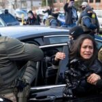 Several ICE agents attempting to place a woman into a vehicle as she cries and struggles to avoid being taken away