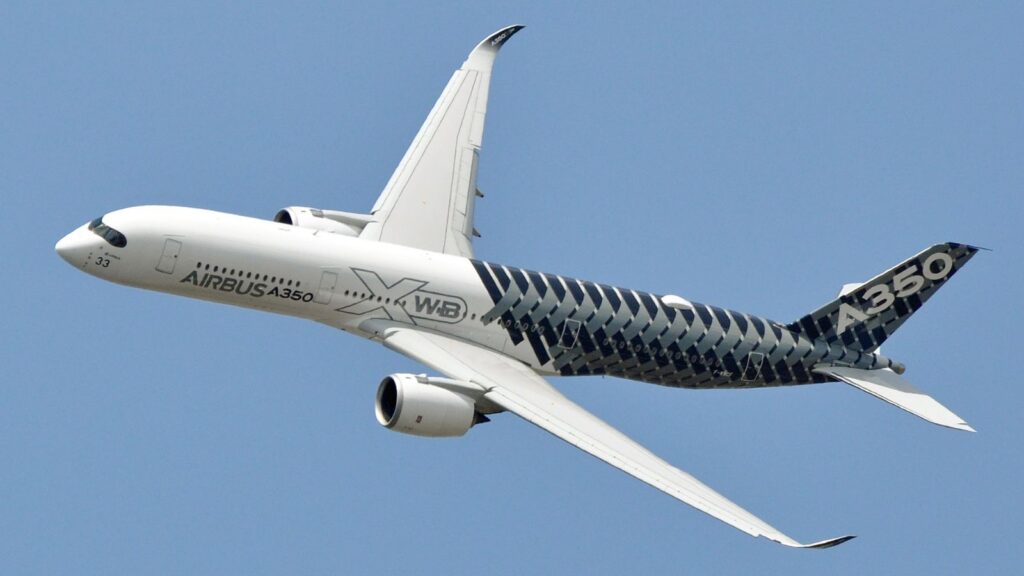 A black-and-white Airbus aircraft flying through the sky, displaying its imposing size
