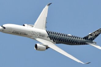 A black-and-white Airbus aircraft flying through the sky, displaying its imposing size