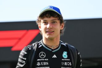 The young Formula 1 driver walking with the trophy in his hand, wearing his striking black racing suit and a matching black cap