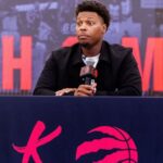 The newly retired basketball player sitting in front of numerous news reporters, smiling and chatting with them