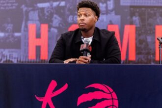 The newly retired basketball player sitting in front of numerous news reporters, smiling and chatting with them
