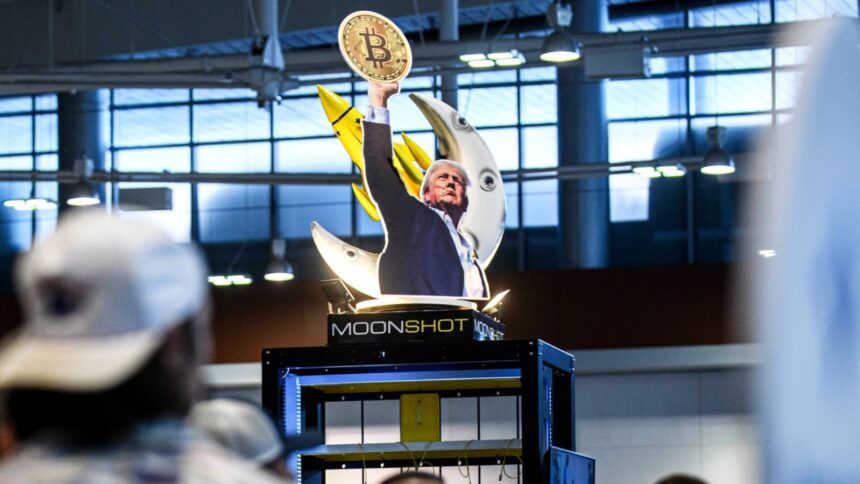 A cardboard cutout of Trump holding a Bitcoin coin high in the air