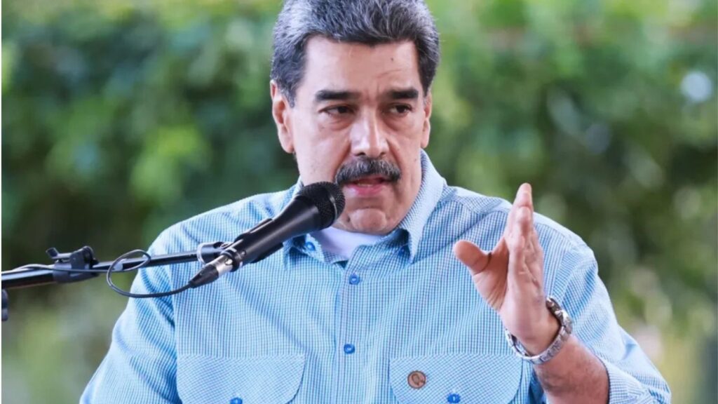 The former president of Venezuela speaking into a microphone while wearing a blue shirt with white checkered patterns