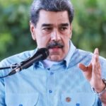 Nicolás Maduro to face trial in the United States in 2027 The former president of Venezuela speaking into a microphone while wearing a blue shirt with white checkered patterns