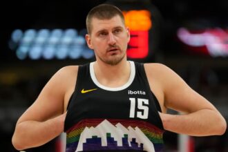 Jokić adjusting his uniform before the start of a basketball game