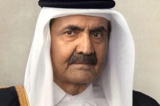 The leader of Qatar looking directly at the camera while wearing his country's traditional attire