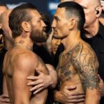 Both fighters stare each other down face-to-face, surrounded by security to prevent the tension from escalating
