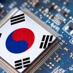 A small, high-tech microchip placed on a motherboard featuring the South Korean flag