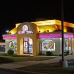 A Taco Bell restaurant with its colorful, eye-catching lights illuminated at night
