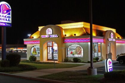 A Taco Bell restaurant with its colorful, eye-catching lights illuminated at night