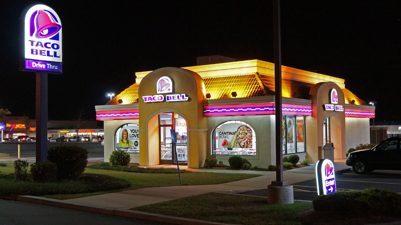 A Taco Bell restaurant with its colorful, eye-catching lights illuminated at night