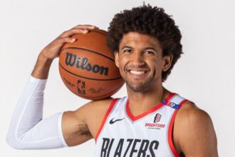 The Los Angeles Lakers' new player holding a basketball close to his face while posing for a photograph
