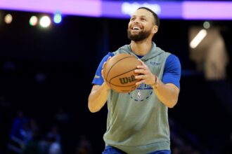 Curry taking a free throw while smiling during a practice session