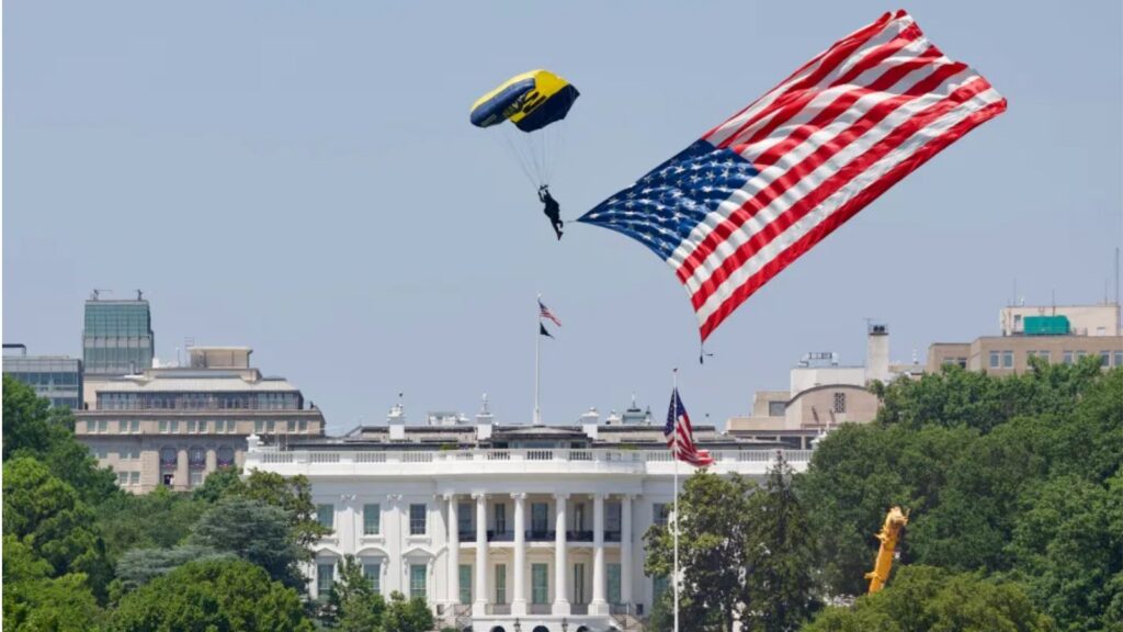 A man waving the United States flag while flying in a helicopter
