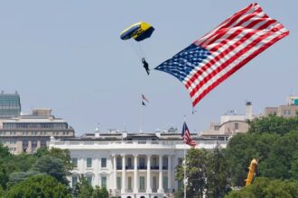 A man waving the United States flag while flying in a helicopter