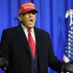 Donald Trump enthusiastically shouting while wearing a red cap bearing his name