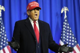 Donald Trump enthusiastically shouting while wearing a red cap bearing his name