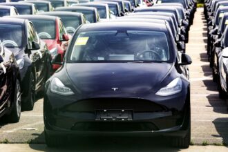 Several Tesla vehicles lined up in rows and covered to protect them from the sun