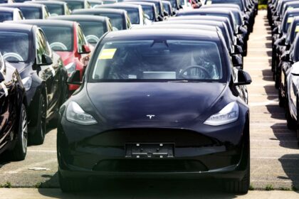 Several Tesla vehicles lined up in rows and covered to protect them from the sun