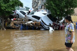 A woman looking at a pile of cars swept away by the heavy rains hitting China
