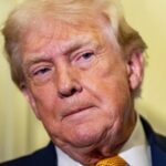 "Donald Trump peeking around a wall with a very serious expression on his face