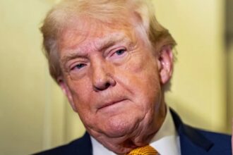 "Donald Trump peeking around a wall with a very serious expression on his face
