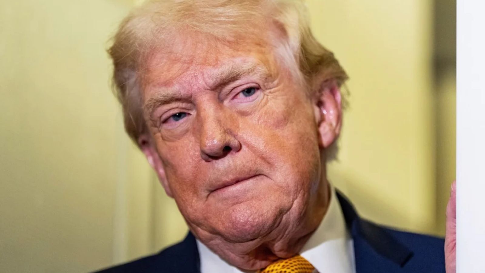 "Donald Trump peeking around a wall with a very serious expression on his face