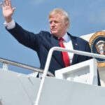Trump waving to people as he boards his private jet