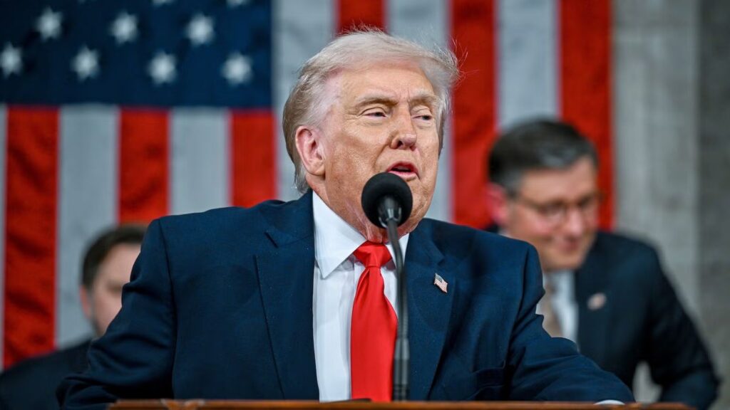 "Trump speaking into a microphone in front of a large crowd