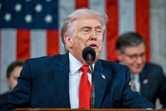 "Trump speaking into a microphone in front of a large crowd