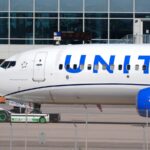 An aircraft from the airline parked at an airport, featuring its iconic white livery and blue lettering