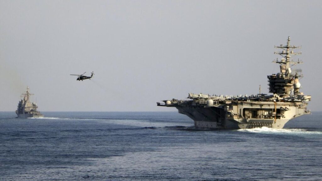 United States launches new strikes as tensions with Iran continue to escalate A massive U.S. aircraft carrier sailing across the sea while a helicopter closely follows it from the air