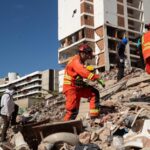 Several rescue workers walking across the rubble in search of injured survivors