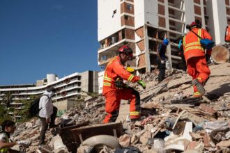 Several rescue workers walking across the rubble in search of injured survivors