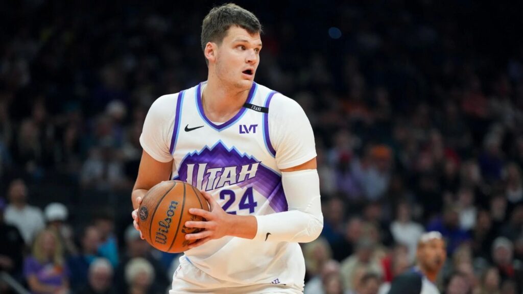 The newest Los Angeles Lakers player wearing his former team's uniform while holding the basketball tightly to protect it from his opponents