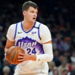 The newest Los Angeles Lakers player wearing his former team's uniform while holding the basketball tightly to protect it from his opponents